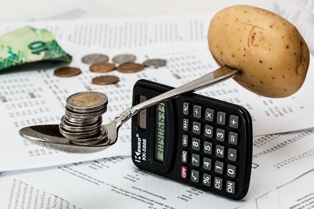 a spoon with a potato and coins